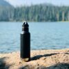 black and gray sports bottle on brown sand near body of water during daytime