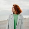 A woman with red hair standing on the beach