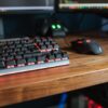 Contemporary personal computer monitors with programming codes placed on desk with backlit keyboard and mouse in light room